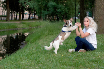 girl with her dog sitting on the grass in the park
