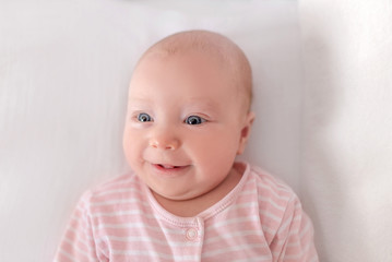 Little baby in a white crib in a good mood.