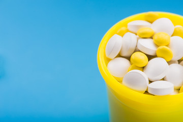White and yellow vitamins pills in container