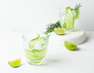 Drink from fresh cucumber juicy lime and a sprig of rosemary in glass glasses on a white background. Selective focus.
