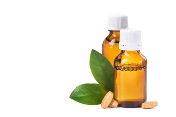 Bottle with liquid medicine, pills and green leaf isolated