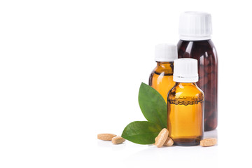Bottle with liquid medicine, pills and green leaf isolated