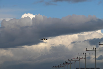 Fototapeta na wymiar Landebahn Befeuerung auf Masten an der Landebahn Nordwest am Flughafen Frankfurt und 3 Flugzeuge im Anflug bei starker Bewölkung - Stockfoto