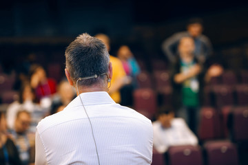 Speaker at business conference and presentation is listening question. Teacher in front of full...