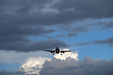 Fototapeta na wymiar Helle und dunkle Wolken und Flugzeug im Landeanflug - Stockfoto