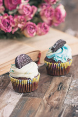 Handmade chocolate muffins with decorations. Book and a bouquet of roses, blurred background