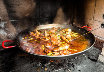 Cooking and making a traditional Spanish Paella over open fire.