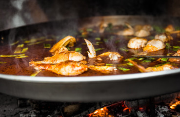 Cooking and making a traditional Spanish Paella over open fire.