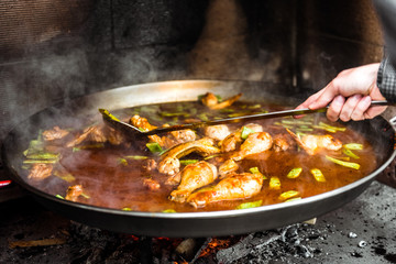 Cooking and making a traditional Spanish Paella over open fire.