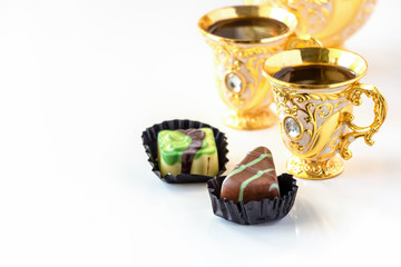 Still life with traditional golden arabic coffee set with dallah, cup and chocolate candy. White background.