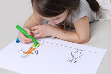 Girl in bright clothing draws a picture of the family. Light room