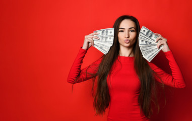 Young pretty woman in red dress hiding behind bunch of money banknotes