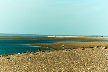 Fototapeta premium Beach with blue sky and against the light, soft brown sand colors, intense blue, soft blues and white line of the horizon and saturation of colors.