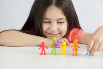 Obraz na płótnie Canvas Happy family figurines. A small child plays with colored plastic figures. Mom, dad, brother, sister, siblings. Family symbol. Adoption. Full family. Face out of focus. 