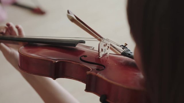 View of female violinist playing fast melody on the strings with fiddlestick