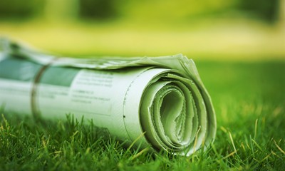 Newspaper on green grass outdoors background