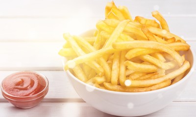 Paper box with pile of appetizing french fries over white planks background