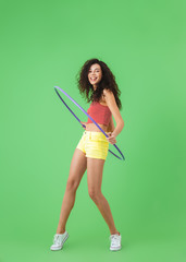 Photo of athletic woman 20s wearing summer clothes doing exercises with hula hoop during workout - obrazy, fototapety, plakaty