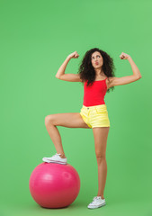 Image of strong woman 20s wearing summer clothes doing exercises with fitness ball during aerobics