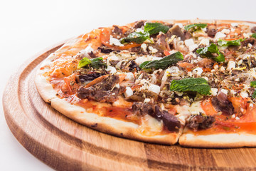 Pizza with mint on a wooden circular board isolated on white background