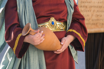 A woman in a biblical costume holds a clay pitcher