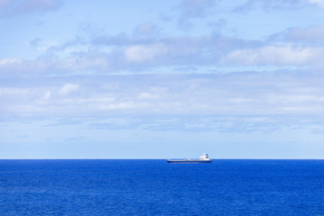Industrial tanker sailing across ocean horizon.
