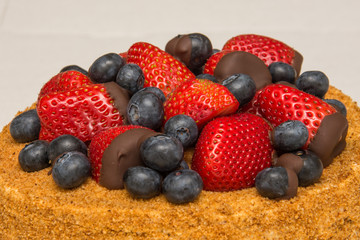A home made honey cake with strawberries and blueberries on top