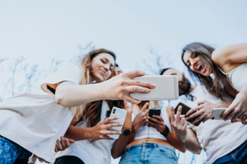 Group of five friends in the street with smartphone