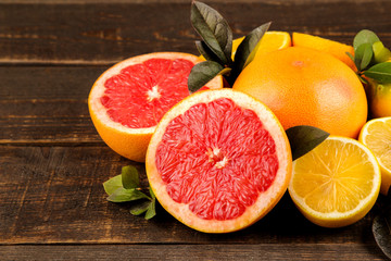 Citrus fruit. Various citrus fruits with leaves of lemon, orange, grapefruit on a brown wooden table. close-up