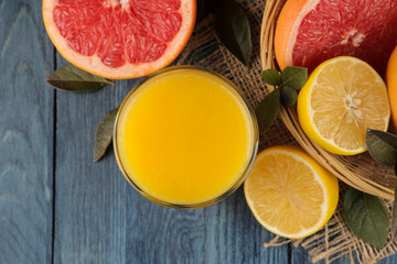 Citrus fruit. various citrus fruits with leaves of lemon, orange, grapefruit in a basket and orange juice on a blue wooden table. top view