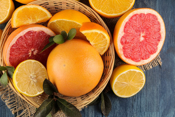 Fototapeta na wymiar Citrus fruit. various citrus fruits with leaves of lemon, orange, grapefruit in a basket and orange juice on a blue wooden table. top view