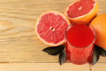 Citrus fruit. Fresh grapefruit with leaves and juice on a natural wooden table. close-up