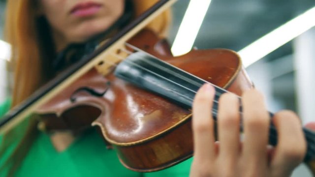 A person uses fiddlestick to play wooden violin.