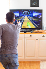 A man playing video game without joystick at home. Cheerful father with family playing bowling and having fun with new trends technology. Gaming concept