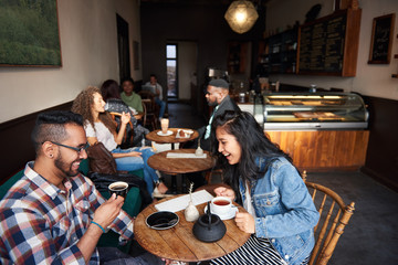 Diverse people sitting at cafe tables talking over coffee