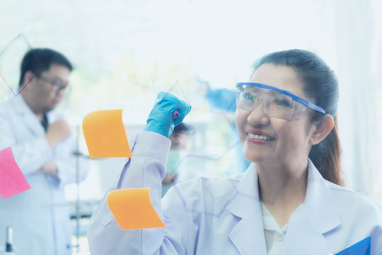 Team work Scientists analyzing study data and evaluating microscope success for work shop.  Health care researchers doing some research with dropper chemical testing working in  science laboratory.