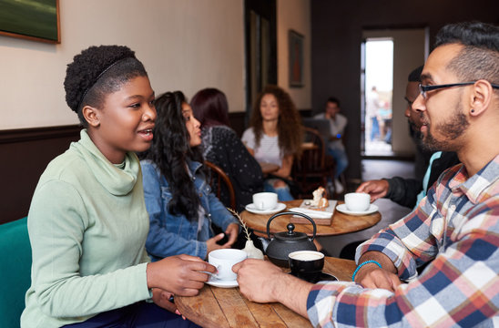 Diverse young friends talking over drinks in a cafe