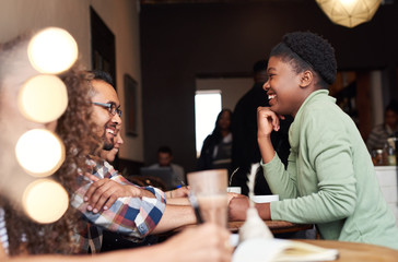 Young woman laughing while talking with friends in a cafe
