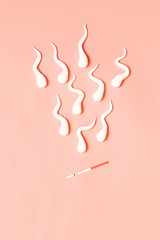 Medical concept. Figures of sperm and pregnancy test on living coral background.