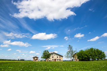 Paesaggio di campagna con cielo nuvoloso e casa rurale emiliana 