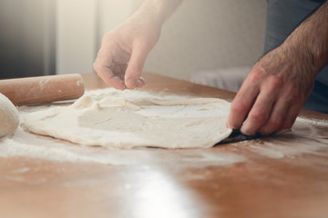  A man is cooking pizza. Closeup of male hands and dough.