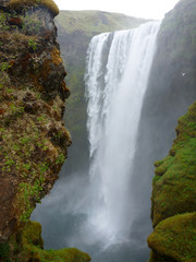 water cascade from Skogafoss Waterfall, Iceland viewed between two cliff rocks