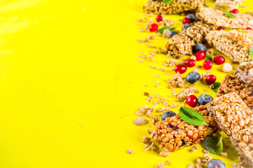 Cereal granola bars with nuts, fruits and berries, bright yellow background top view copy space