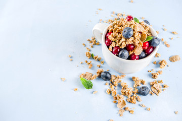 Small cup with breakfast oat granola, cereal muesli, nuts and berries. Healthy breakfast or snack concept, Bright trendy background, Top view copy space