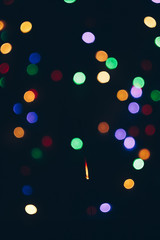 sparkling Bengal sparklers sticks in flames on a black background with lights bokeh. christmas theme new year background. holiday card