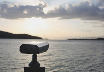 A binoculars to watch the sea on a summer evening with the ocean on the background / with copy space for the text / bird watching / sea / warm colors