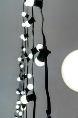 Fototapeta na wymiar Closed up white LED illuminated lightbulb with black nylon braided cover cord and extension on grey background
