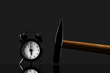 wake up with a hammer on a black background. Black old style alarm clock isolated