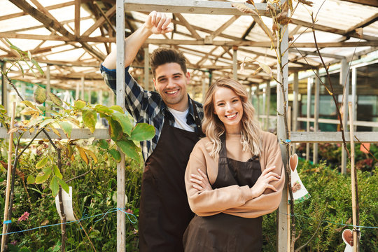 Happy young two colleagues gardeners at the workspace over plants