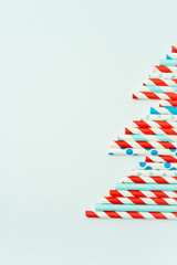 Obraz premium Colorful straws for drinking drinks in the shape of Christmas trees on a bright background. New year holiday background.